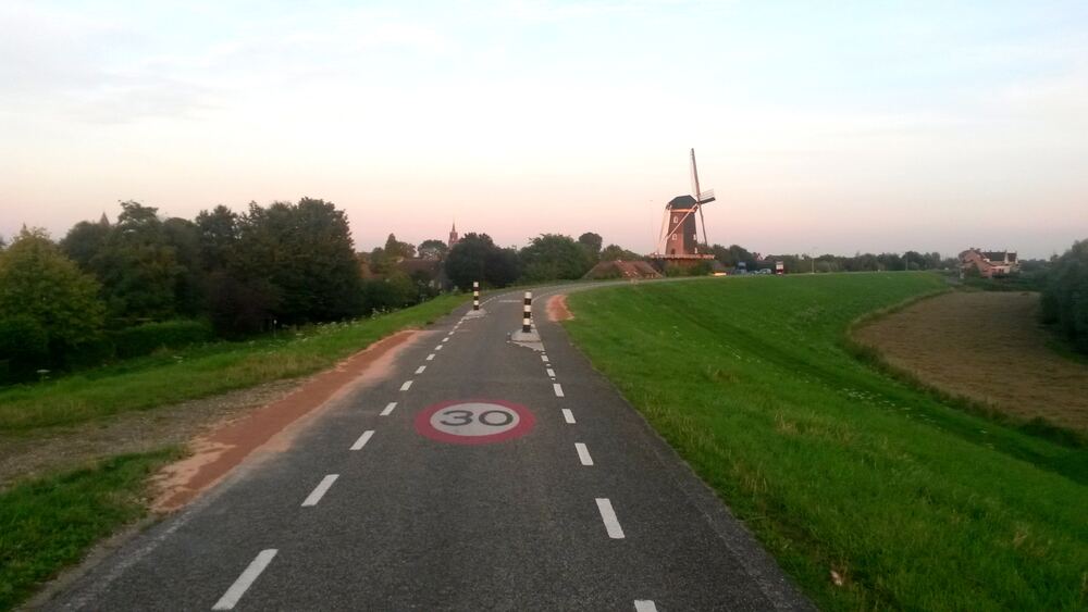 De Waaldijk met een molen in het avondlicht